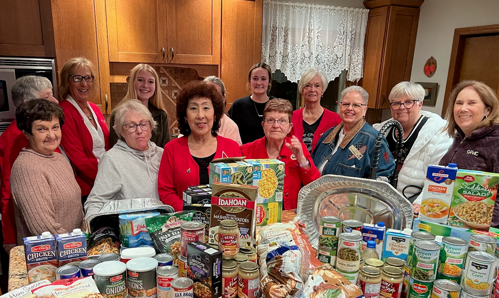 Women Volunteers standing behind a table filled with food donations.